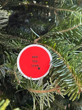 Load image into Gallery viewer, red, 1.5&#39;, round sticker with white border and black message, see the love, with a small black heart at the bottom right of the letters 
